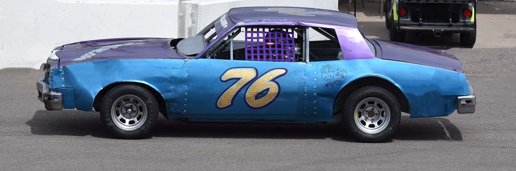 A blue and purple stock car with 76 on the door